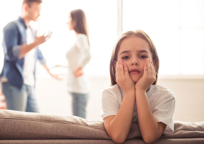 Trauriges Kind, Eltern streiten im Hintergrund