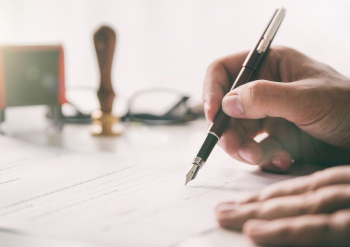 Eine Person unterschreibt etwas mit einem Füller